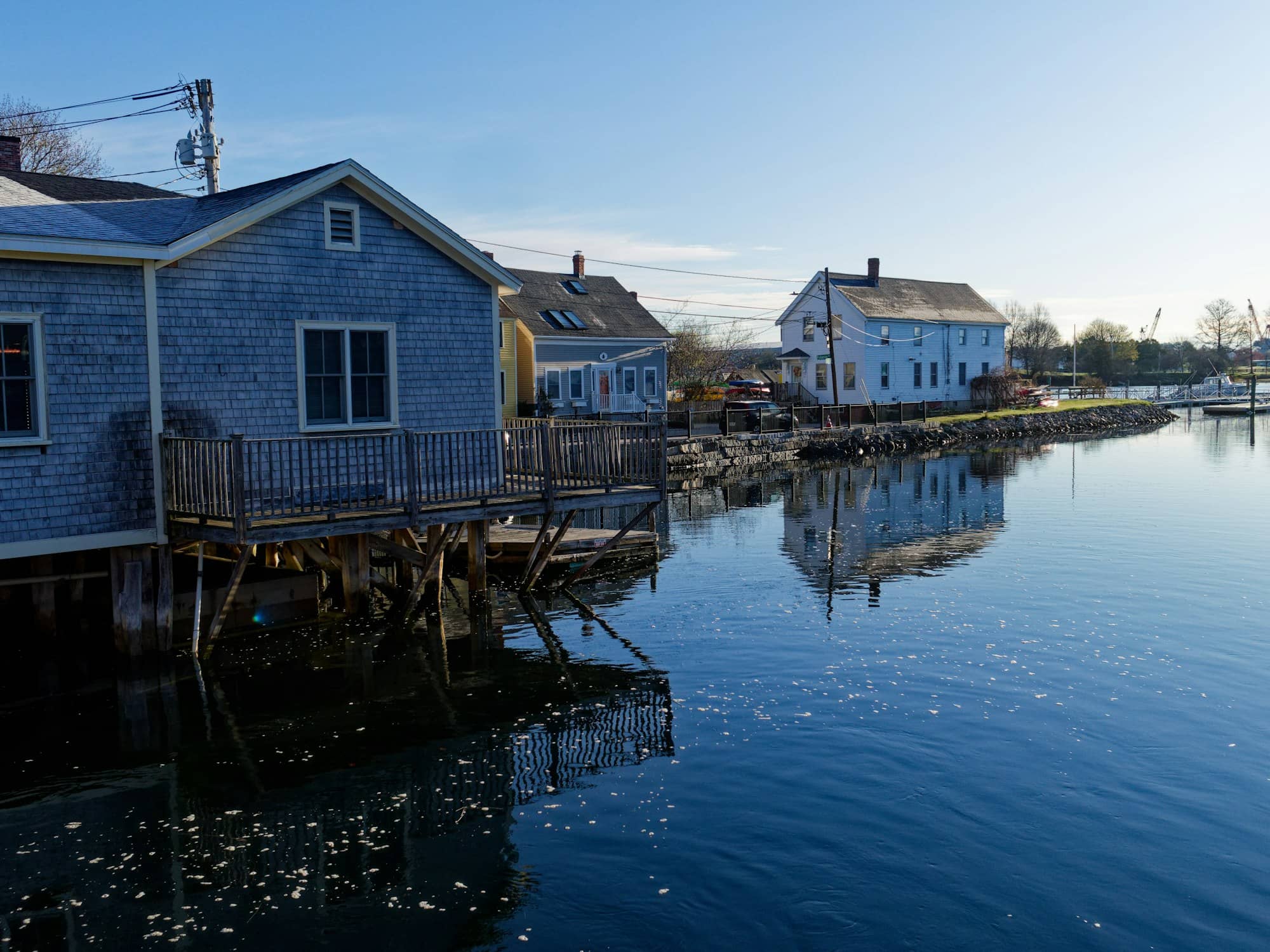 Blue buildings reflected in calm water under a clear sky.