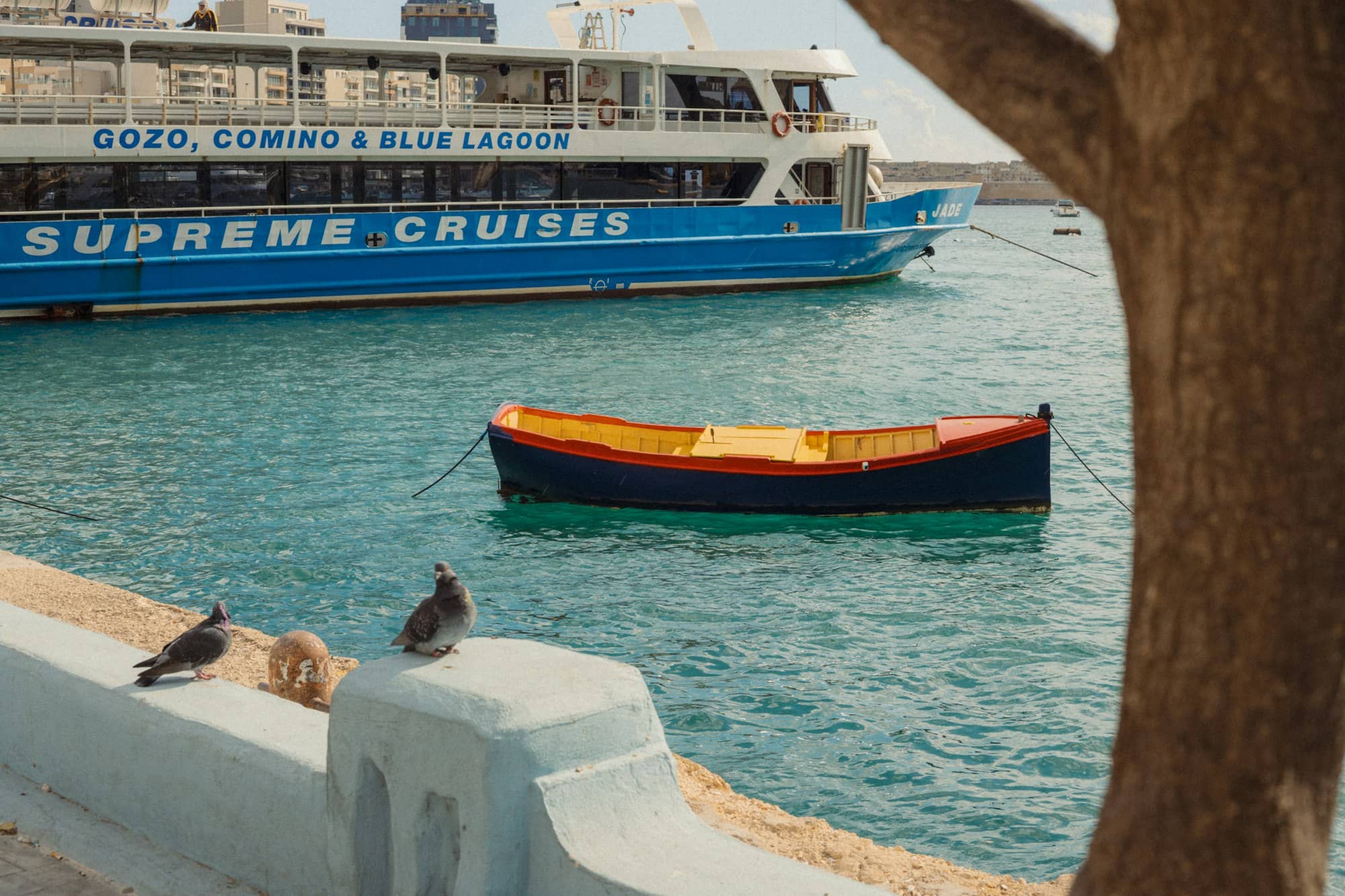 A small boat floats near a large cruise ship.
