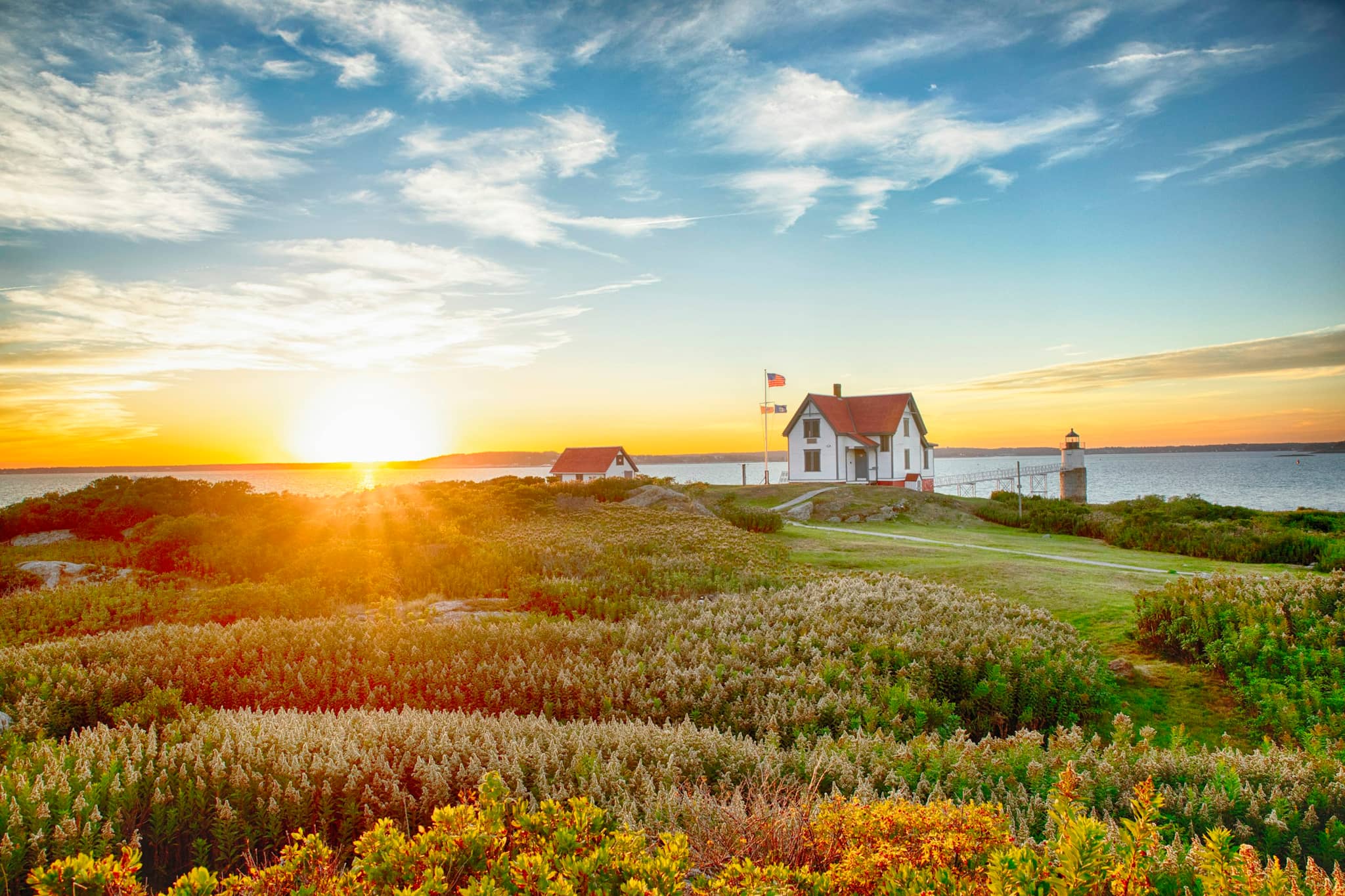 A lighthouse keeper’s house on a headland at sunset, autumn scrub in the foreground