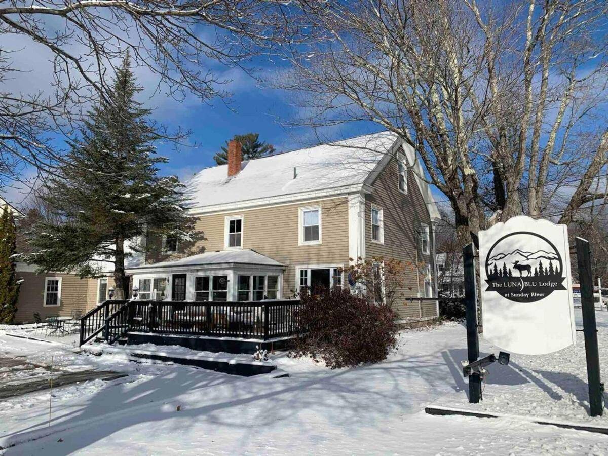 a house with a sign in front of it in the snow at The LunaBlu Lodge Sunday River in Bethel