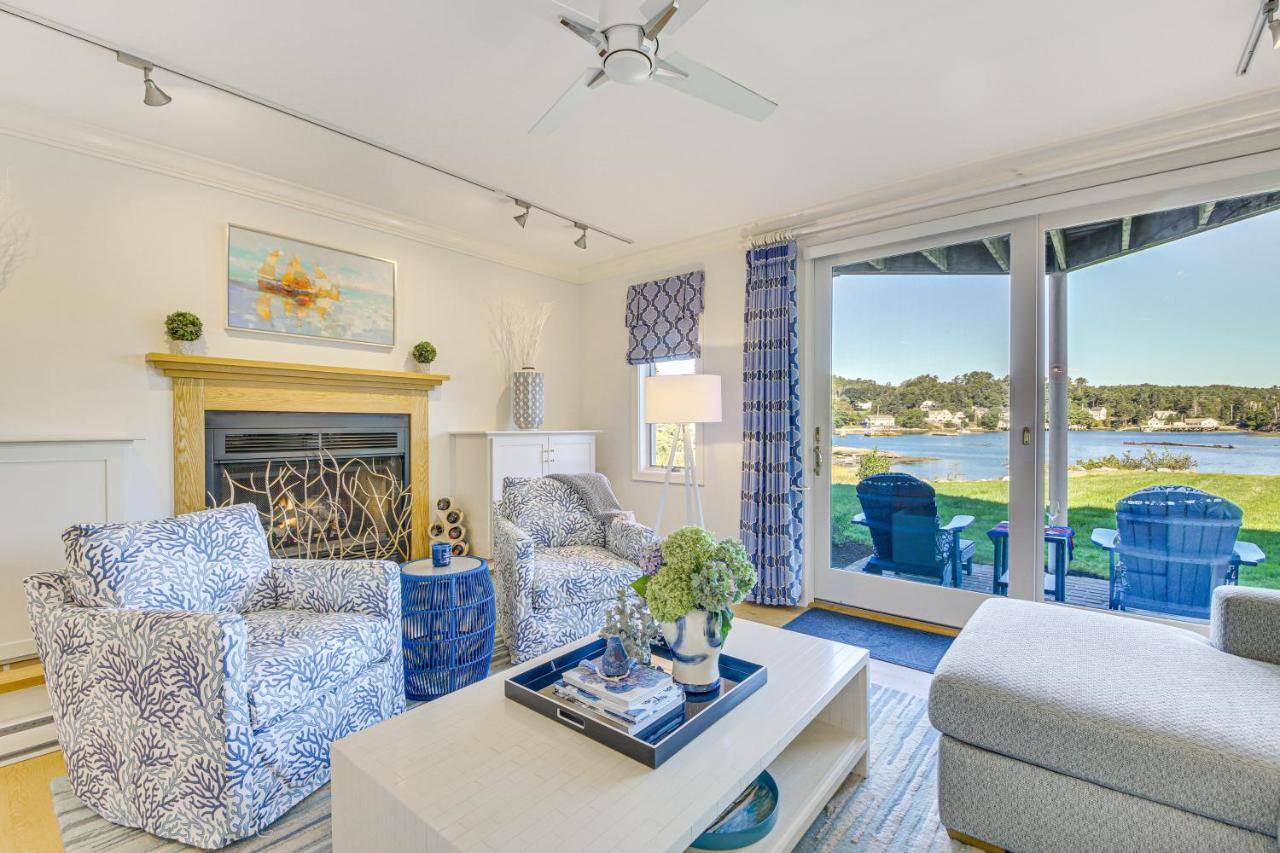 a living room with two chairs and a fireplace at Waterfront Condo Walk to Downtown Boothbay Harbor in Boothbay Harbor