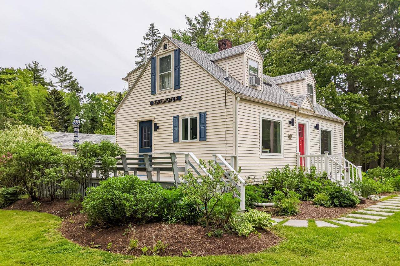 a white house with a porch and a garden at Riverwatch in Boothbay