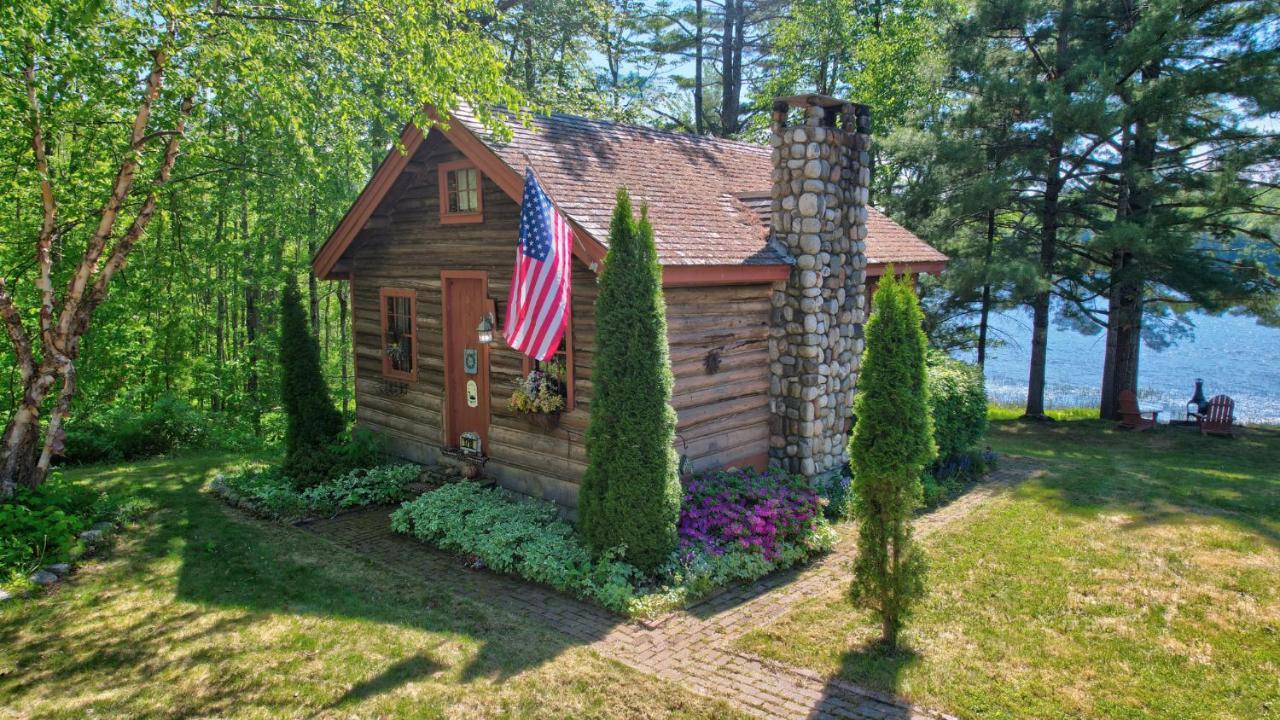a small house with an american flag in the yard at Authentic Maine Log Cabin Lakefront Cozy in Bucksport