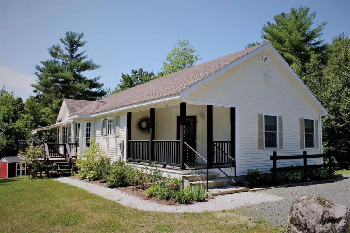 a white house with a porch and a yard at Nestled in Nature Acadia in Ellsworth