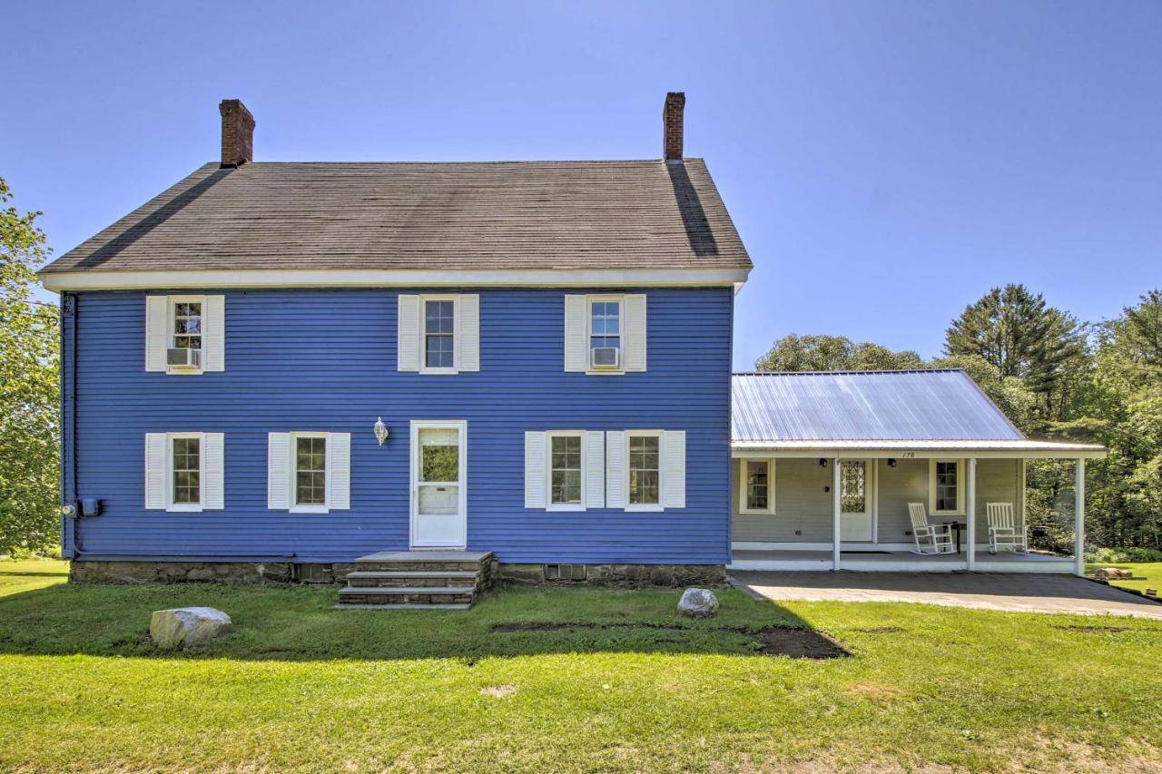 a blue house with a porch and a yard at Riverfront Coastal Escape with Deep Water Dock! in Fort Edgecomb
