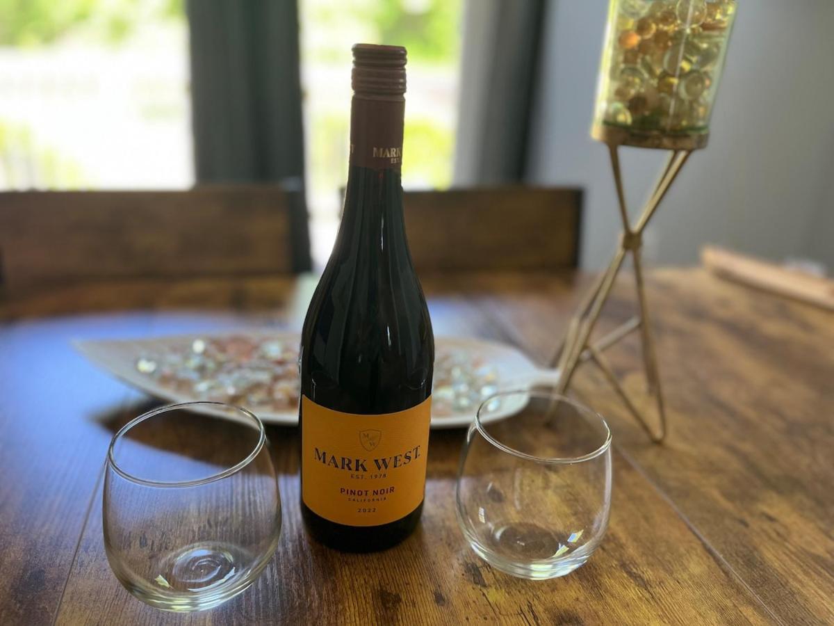 a bottle of wine next to two glasses on a table at Cozy Retreat with Private Backyard Oasis