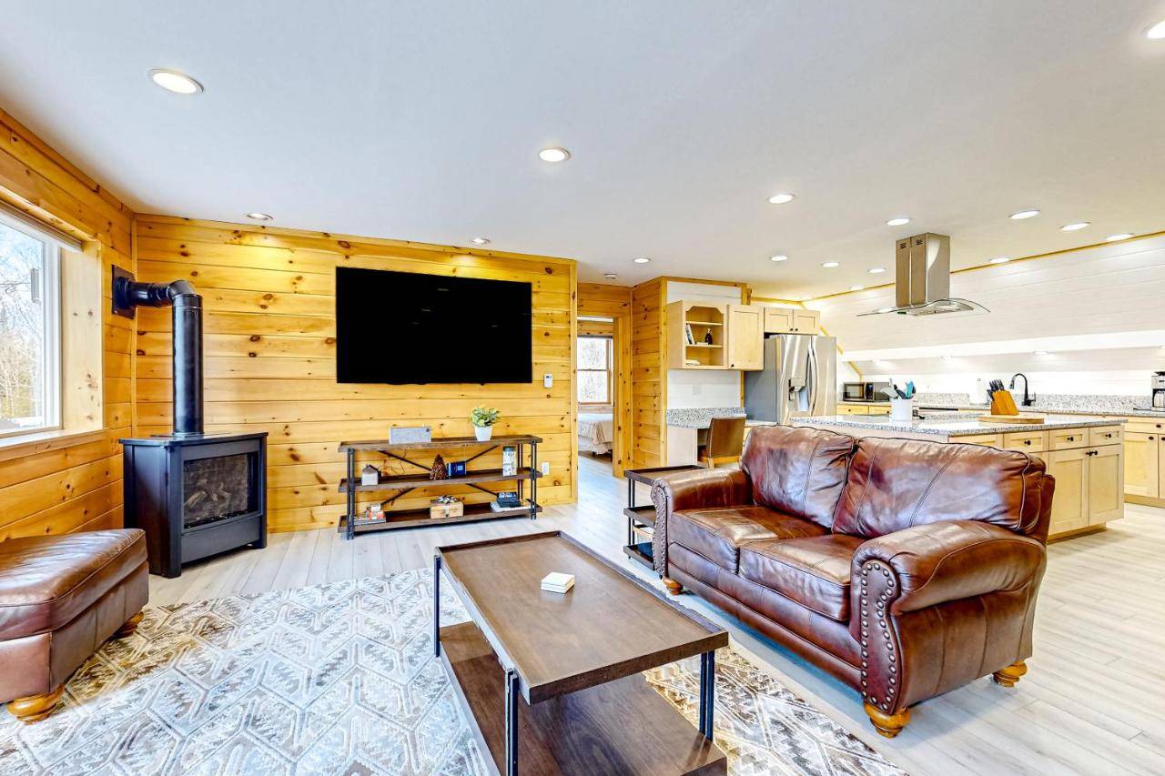 a living room with leather furniture and a flat screen tv at Moosehead Lake Home Base in Rockwood