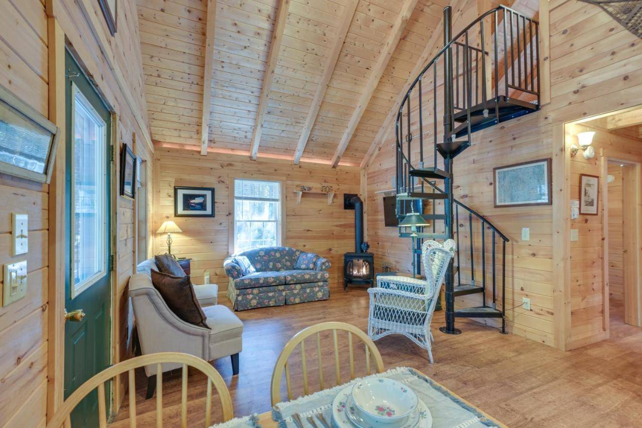 a living room with a spiral staircase in a log cabin at Maine Lodging Near Acadia National Park! in Bernard