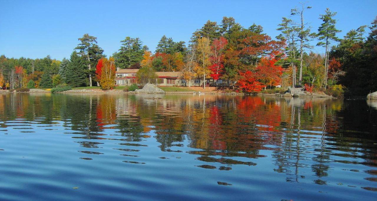 a lake in front of a house with colorful trees at Alamoosook Lakeside Inn Orland in Orland