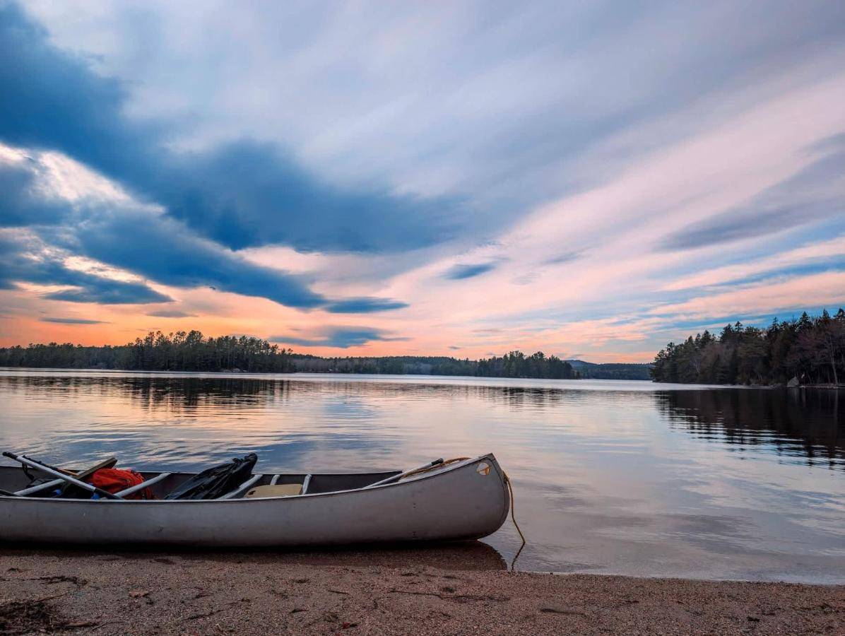 a boat sitting on the shore of a lake at Acadia Sunset Fishing Cabin #3 family beach fire pit in Sullivan